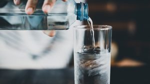 Botella de agua mineral sirviendo un vaso