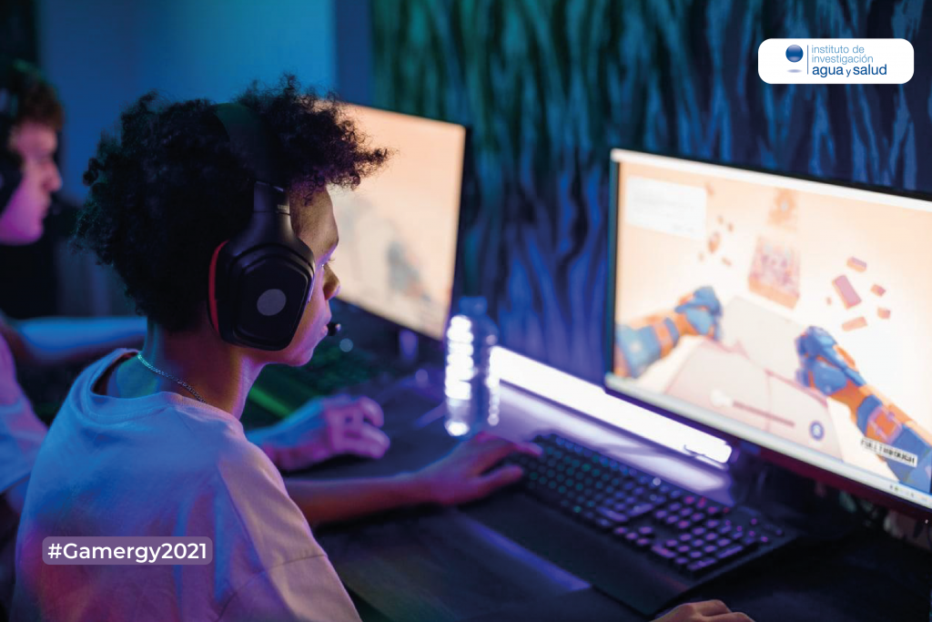 Un joven juega con su ordenador a un videojuego y mantiene cerca una botella de agua mineral